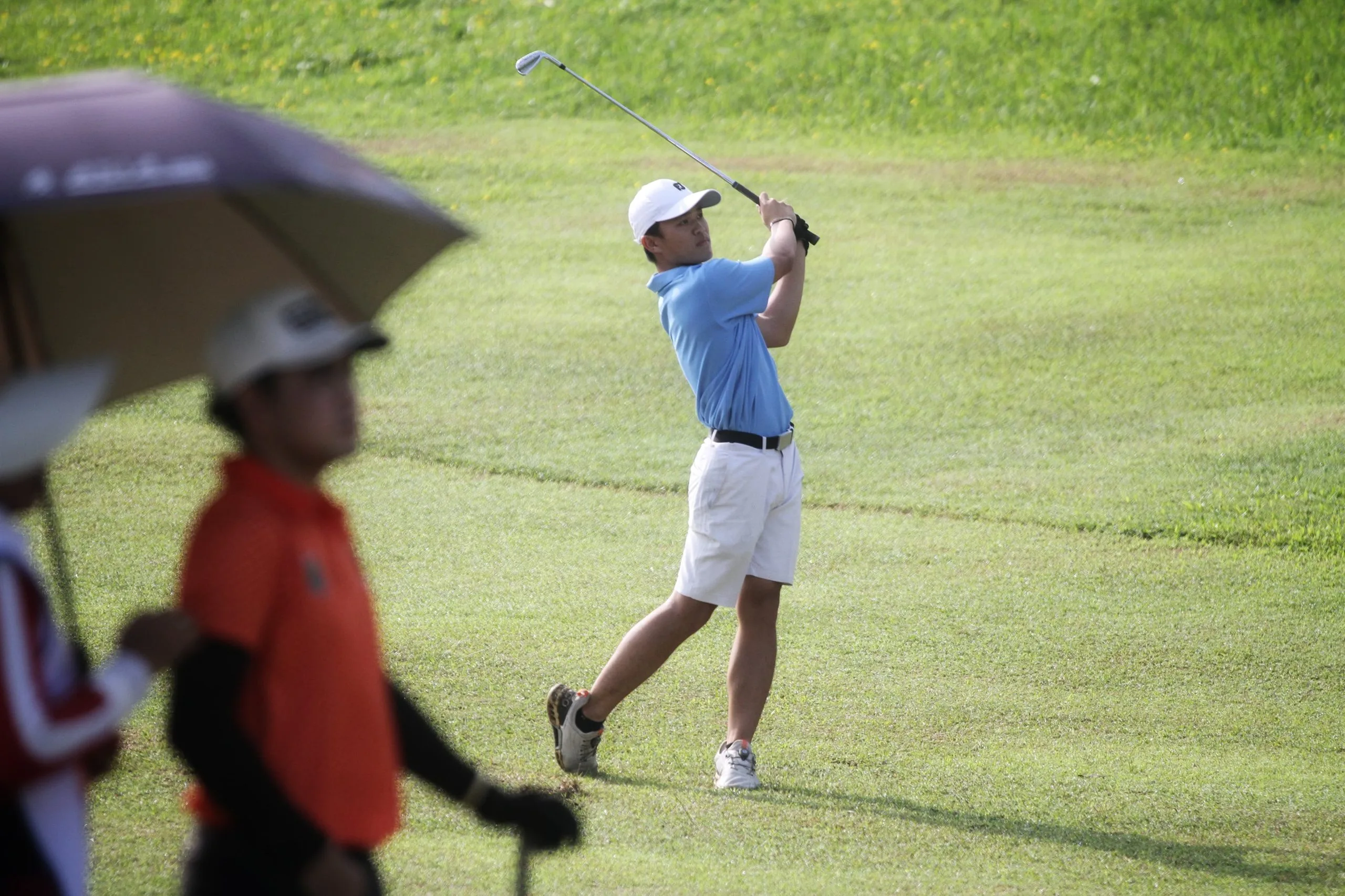 Pegolf Kota Surabaya William Justin Wijaya (kanan) saat memukul bola di fairway hole 8 Araya Golf Course, Malang, dalam hari kedua cabor golf Porprov IX Jatim 2025. (Foto: PGI Jatim)
