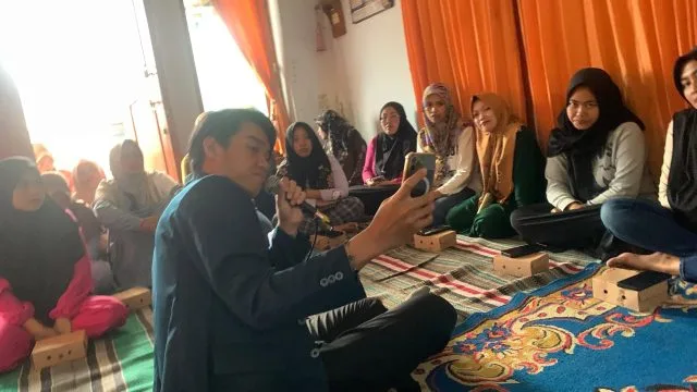 Ketua pelaksana program Daffa Putra Hardian saat menunjukkan cara pemasaran digital kepada ibu rumah tangga pelaku UMKM lokal Desa Wringinanom, Kecamatan Poncokusumo, Kabupaten Malang. (Foto: Dokumentasi Kelompok 36 MMD UB)